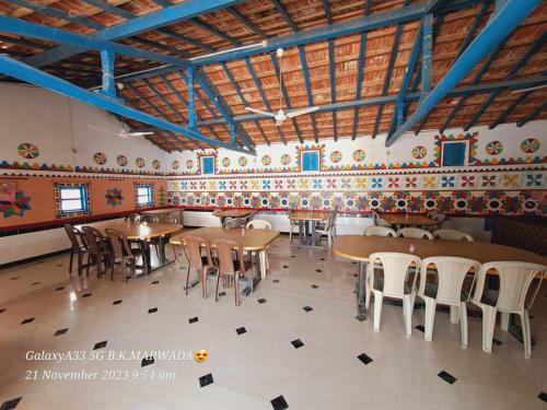 a restaurant with tables and chairs in a room at Rann bhumi village resort in Bherandiāla