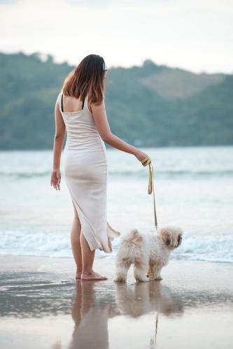 a woman in a white dress walking a dog on the beach at Bucana Beach House North El Nido in El Nido
