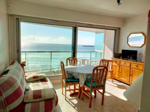 - un salon avec une table et des chaises et une vue sur l'océan dans l'établissement Studio tout confort face à la mer avec balcon - Les Sables-d'Olonne - FR-1-331-41, à Les Sables-dʼOlonne