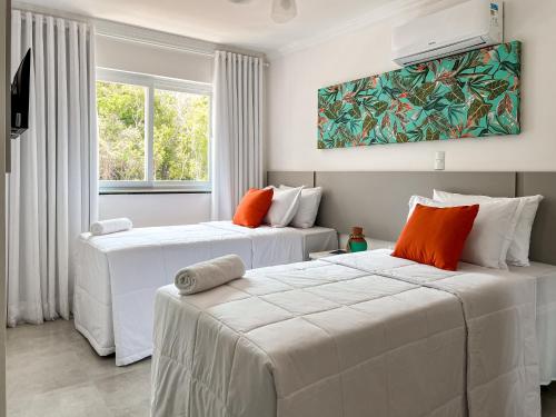 2 weiße Betten in einem Zimmer mit Fenster in der Unterkunft Casa para temporada em Arraial D'ajuda in Porto Seguro