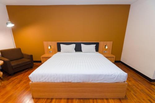 a bedroom with a large bed and a chair at Graha Widya Bhakti at STIESIA Surabaya in Surabaya