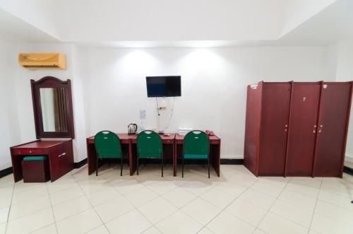 a room with a table with green chairs and a television at Graha Widya Bhakti at STIESIA Surabaya in Surabaya