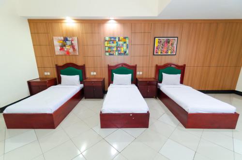 two beds in a room with wood paneling at Graha Widya Bhakti at STIESIA Surabaya in Surabaya