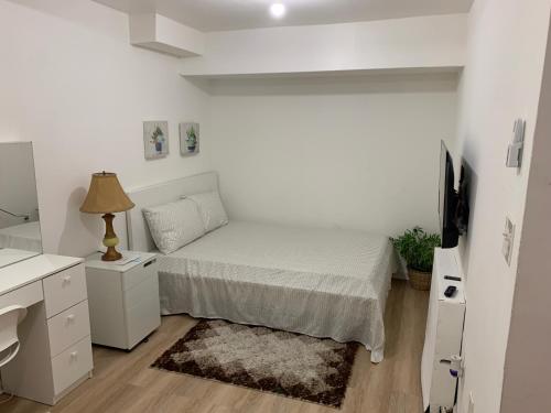 a white bedroom with a bed and a desk at 2265 Bruckner Blvd Apartments in Bronx