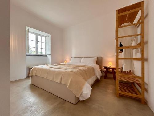 Habitación blanca con cama y escalera en Casa Valentina, en Pedrógão