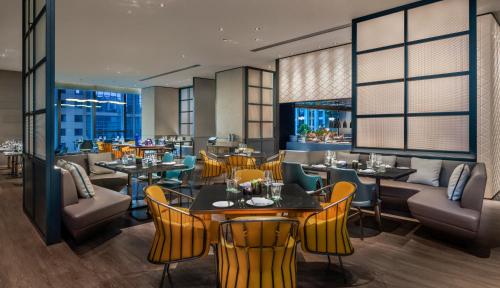 a restaurant with yellow chairs and tables and windows at W Changsha in Changsha