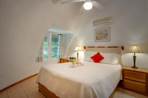 a bedroom with a large white bed with red pillows at Xanadu Island Resort in San Pedro