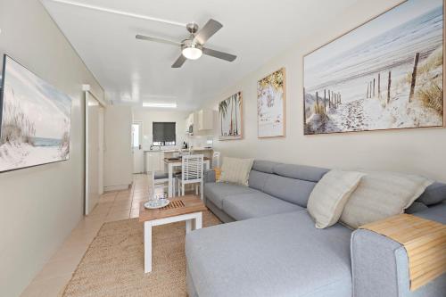 a living room with a blue couch and a table at Sawtell Beach Ocean Sands 3 - Opposite Main Beach and short stroll to Coffee Shops and Restaurants! in Sawtell