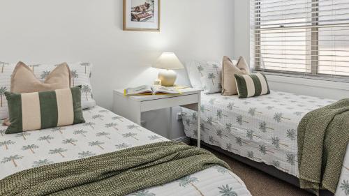 ein Schlafzimmer mit zwei Betten und einem Tisch mit Lampe in der Unterkunft Convent Cove - Penthouse with views over Convent in Yamba