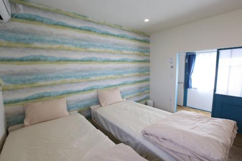 two beds in a room with a striped wall at Breath of the Sea Katakai in Katakai