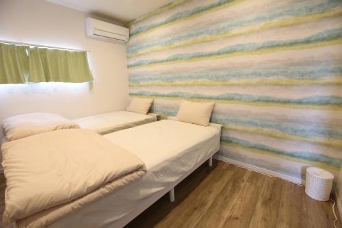 two beds in a room with a colorful wall at Breath of the Sea Katakai in Katakai