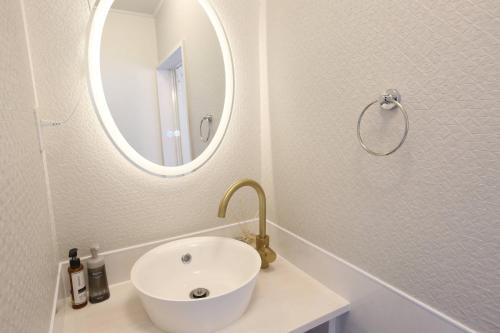 a white bathroom with a sink and a mirror at Breath of the Sea Katakai in Katakai