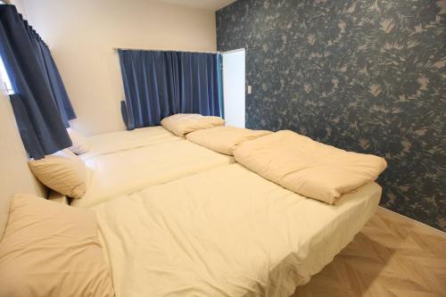 three beds in a room with blue curtains at Breath of the Sea Katakai in Katakai