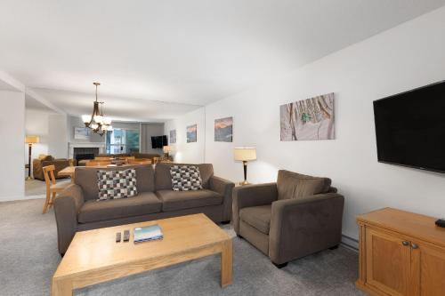 a living room with couches and a flat screen tv at The Woodrun Lodge by Whiski Jack in Whistler