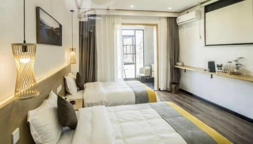 a hotel room with two beds and a large window at Furong Town 373 Jingjingjia Inn in Wang-ts'un