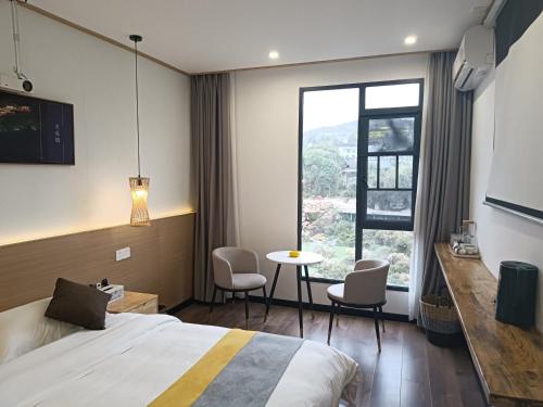 a hotel room with a bed and a table and chairs at Furong Town 373 Jingjingjia Inn in Wang-ts'un