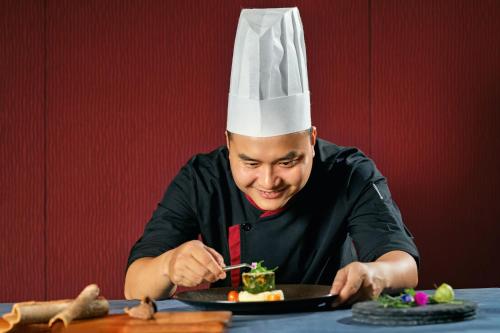 a man in a chefs hat eating a plate of food at Novotel Nha Trang in Nha Trang