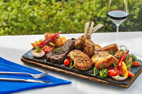 a plate of meat and vegetables with a glass of wine at Novotel Nha Trang in Nha Trang