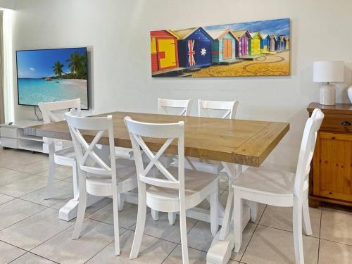 a dining room with a wooden table and white chairs at Unit 3 - Avoca Palms Resort in Avoca Beach