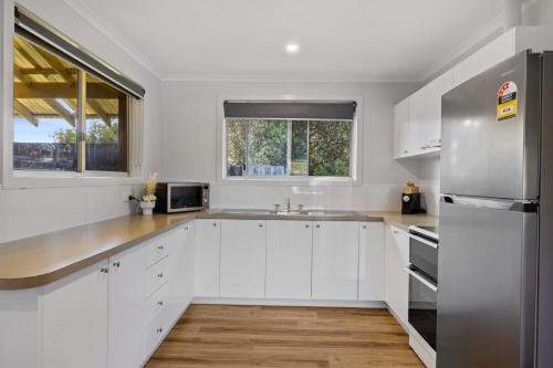 a kitchen with white cabinets and a stainless steel refrigerator at BIG4 Ingenia Holidays Inverloch in Inverloch