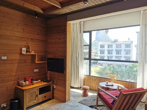 a living room with a table and a large window at Yangshuo Shui Mo Ju courtyard in Yangshuo