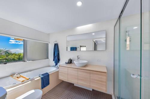 a bathroom with a tub and a sink and a mirror at Large, Luxurious Townhouse Stunning Oceanviews in Airlie Beach