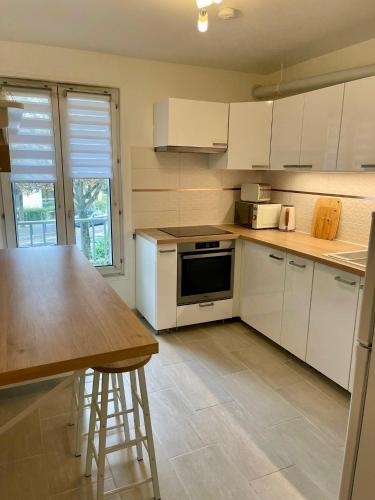 une cuisine avec des armoires blanches et une table en bois dans l'établissement Evasion Paris Orly T2 Charmant et Cosy, à Thiais