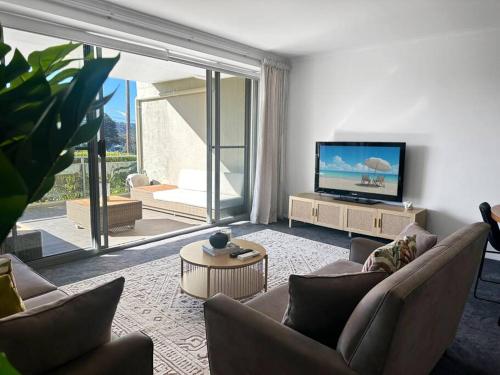a living room with a tv and a couch and a table at Unit 5 - Avoca Palms Resort - 3 bedroom apartment in Avoca Beach