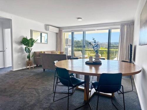 a living room with a table and chairs and a couch at Unit 5 - Avoca Palms Resort - 3 bedroom apartment in Avoca Beach