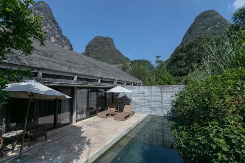 a villa with a pool and mountains in the background at Yangshuo Sugar House in Yangshuo