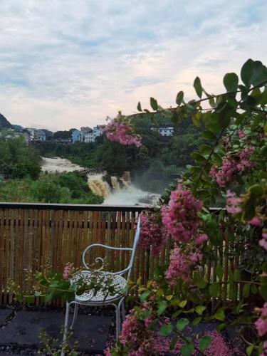 a white chair sitting on a balcony with flowers at 372 Jingjing's Home Inn in Yongshun