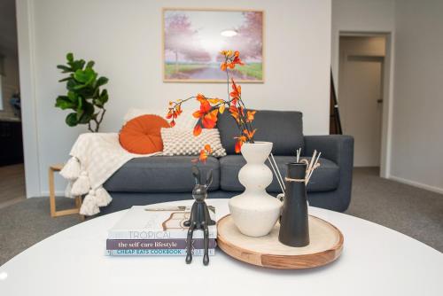 a living room with a table with a couch and flowers at Restful Retreat in Tauranga