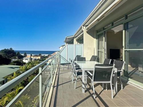 a balcony with a table and chairs and the ocean at Unit 30 - Avoca Palms Resort in Avoca Beach
