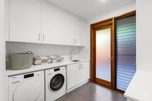 a white laundry room with a washer and dryer at Yangaro in Airlie Beach