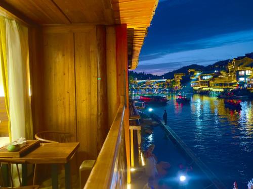 a room with a view of a river at night at Bian Cheng Xing Zi Inn in Fenghuang