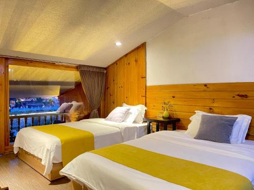 a hotel room with two beds and a balcony at Bian Cheng Xing Zi Inn in Fenghuang County