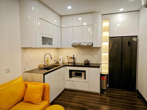 a kitchen with white cabinets and a yellow couch at Ấm cúng, hiện đại, tiện nghi 3! in Hai Phong