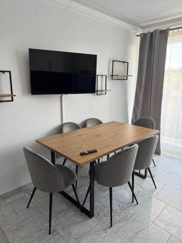 a dining room table with chairs and a flat screen tv at Sabo Apartment in Cluj-Napoca