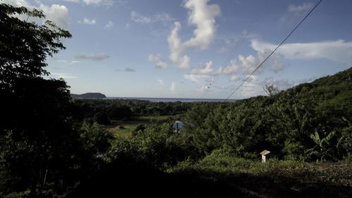 a person walking down a hill in a field at Hilltop Cabin in Black Bay Laborie in Laborie