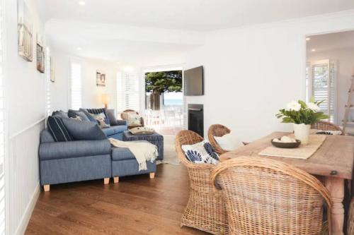 a living room with a couch and a table and chairs at Beach Front House Outdoor Hot Tub Sauna in Patonga