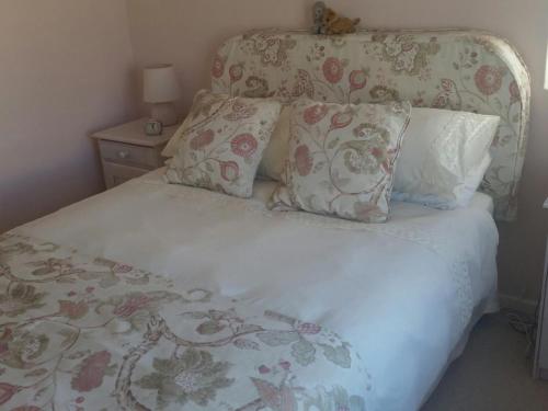 1 cama con cabecero de flores y almohadas en H4 Princess Beach duplex, en Ciudad del Cabo