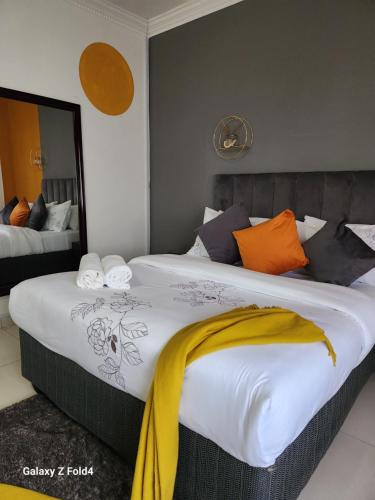 a bedroom with a large bed with a yellow blanket on it at Sunshine Inn in Gaborone