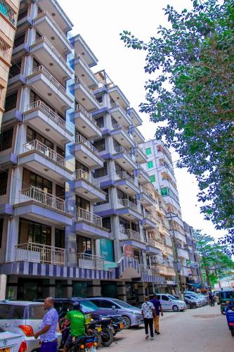 un grand bâtiment avec des voitures garées devant dans l'établissement Sleep Inn Hotel - Kariakoo, à Dar es Salaam