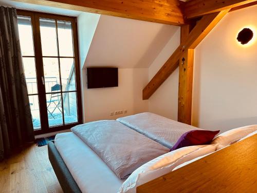 a bed in a room with a large window at Brunnwirt ESSEN & WOHNEN in Fuschl am See