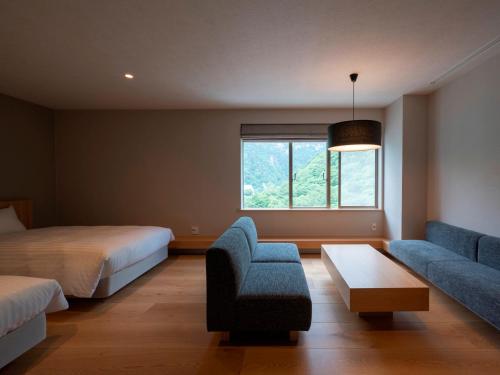 a bedroom with a bed and a couch and a chair at 層雲閣 in Kamikawa
