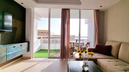 a living room with a couch and a table at The White Waves TF Holiday Apartment Las Americas in Playa Fañabe