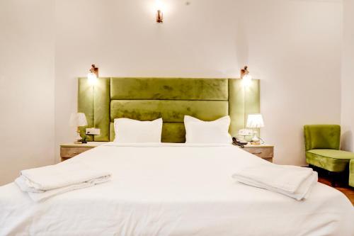 a bedroom with a large white bed with a green headboard at Staybook The Rudveda Resort - Free High Tea near Pool Area in Rāmnagar