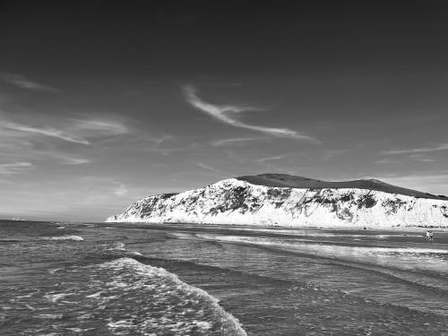 a black and white photo of a mountain in the ocean at Cap à la mer in Sangatte