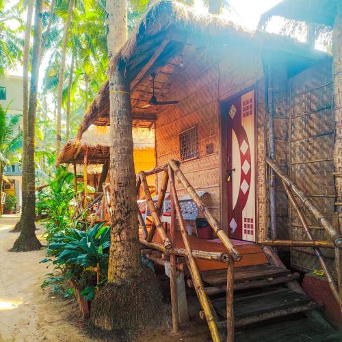 a small shack with a tree in front of it at Dunes Holiday Village in Mandrem