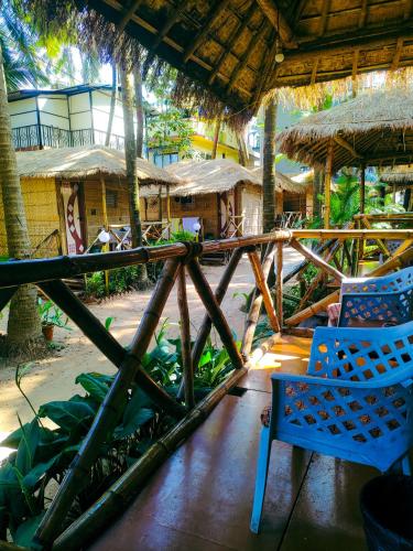 a porch with two chairs and trees and houses at Dunes Holiday Village in Mandrem